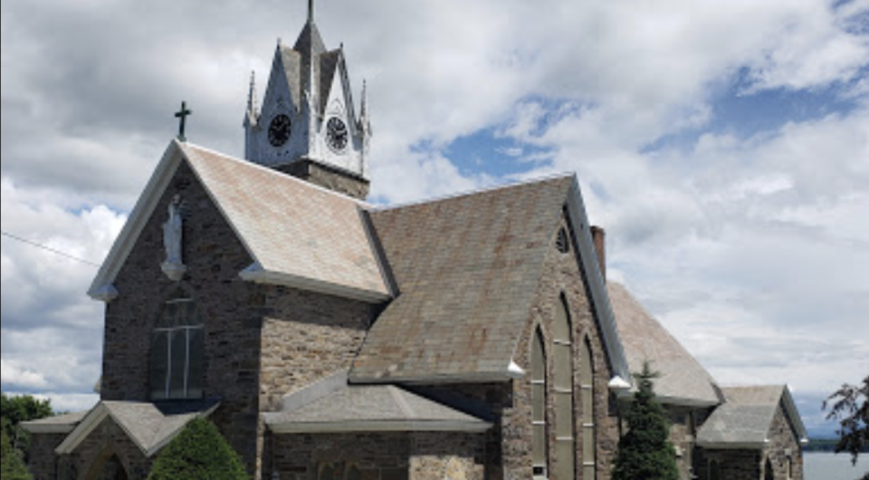 A tall stone church with many roofs and tall steeple.