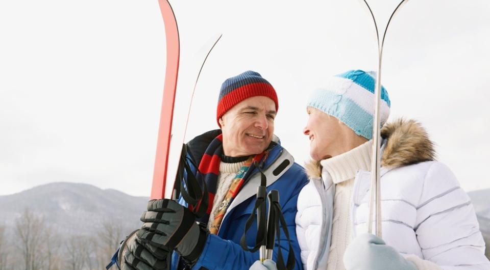 A smiling couple holding snow skis
