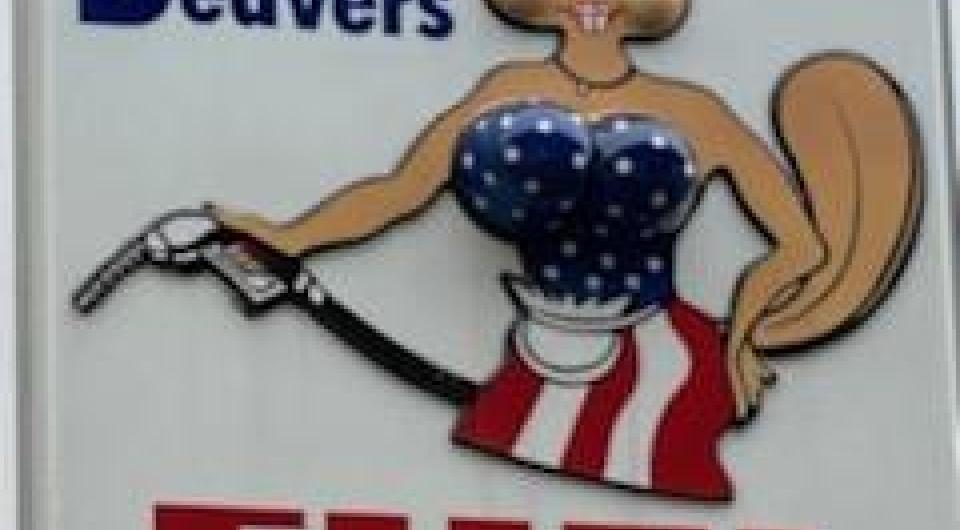 A large white sign with an illustrated beaver in a blue tube top and a white and red stripped skirt pumping gas.
