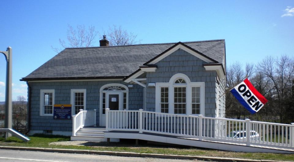 The entry to the grey building with white trim with entry ramp of the former bridge toll house