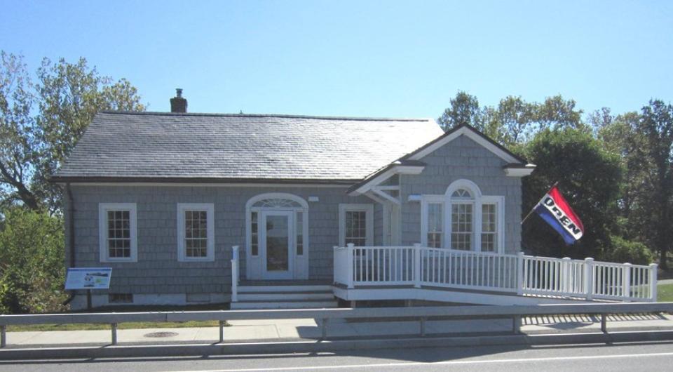The entry to the grey building with white trim with entry ramp of the former bridge toll house