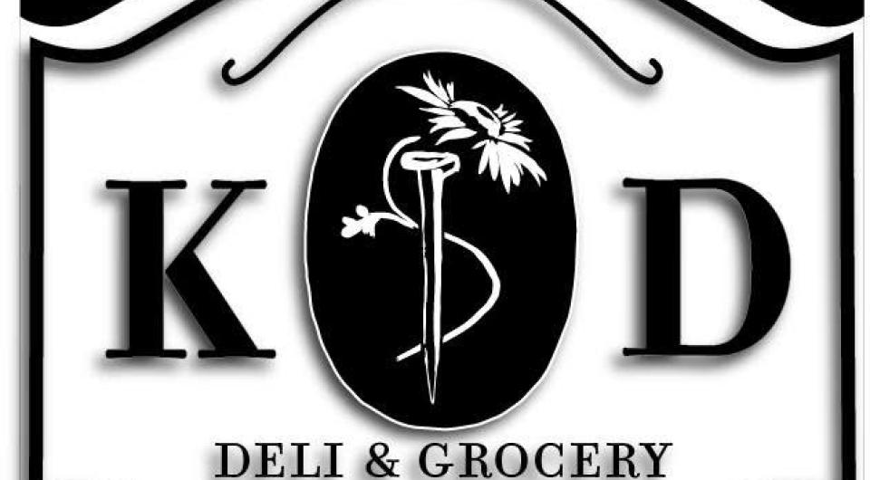 A curved plaque with K D Deli and Grocery with a daisy in the center.