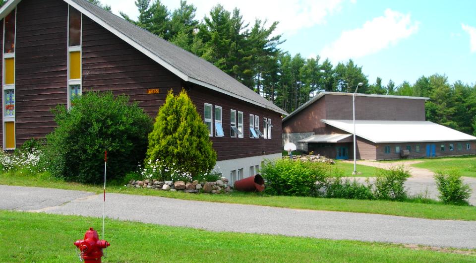 Exterior view of the lush grass and tall glass windows on the brown church.