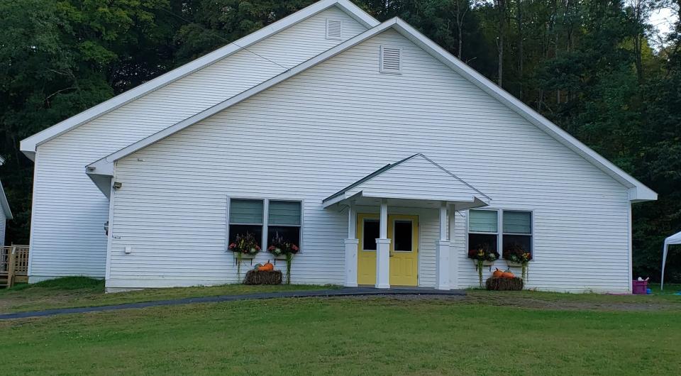 A white church with flower boxes and yellow doors.