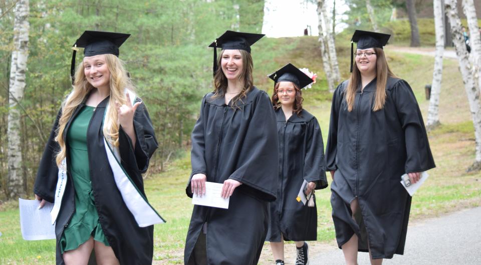 Smiling graduates walk by.