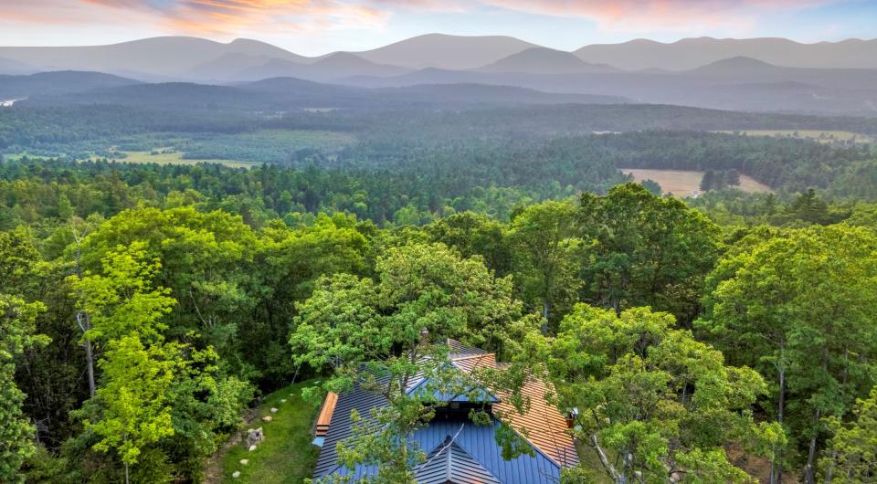 An aerial view of a new home with stunning view of the surrounding mountains and clouds.