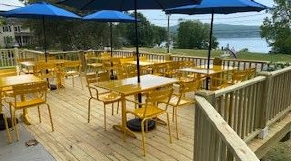 A huge deck with bistro tables and big blue umbrellas overlooking the lake.