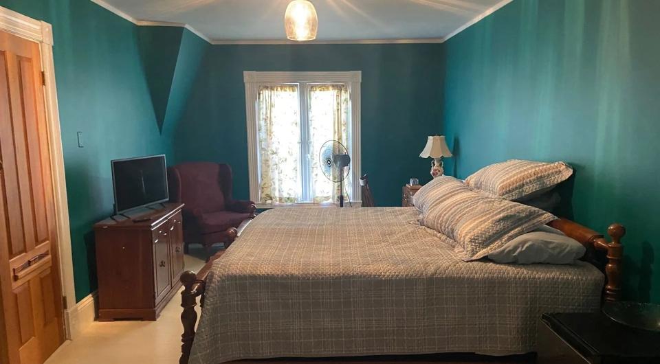 A teal colored room with large bed.