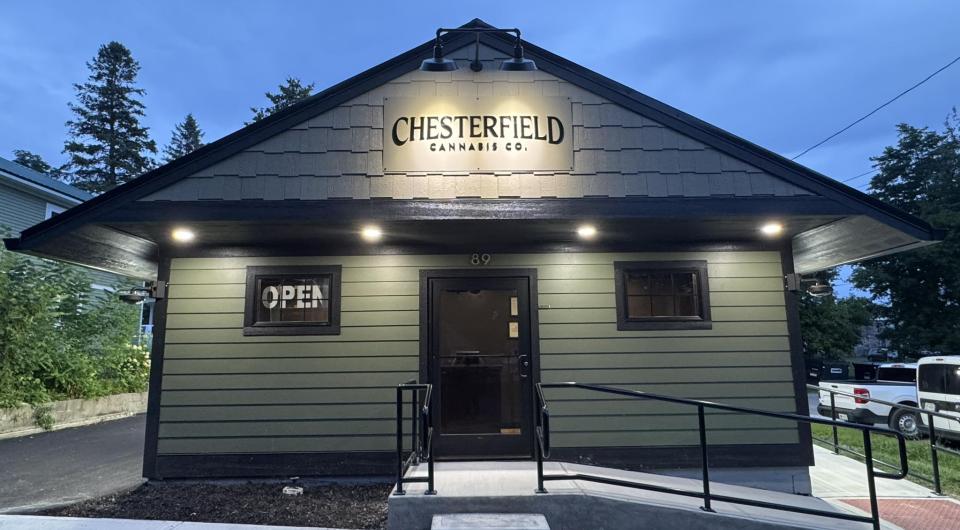 Exterior of the green and black building with concrete steps and ramp with metal handrail.