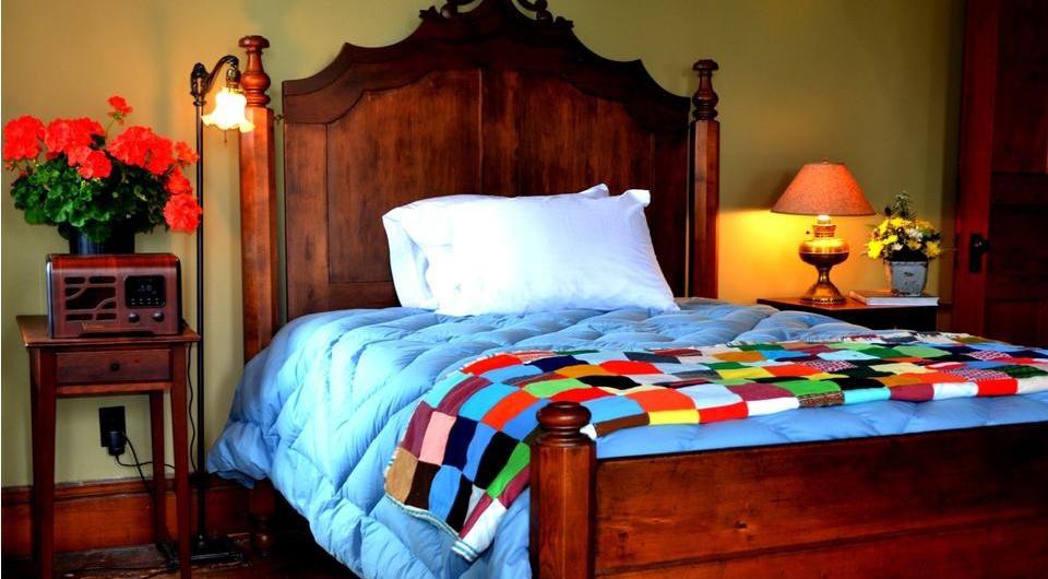 Quilts on the bed with ornate wooden headboard.