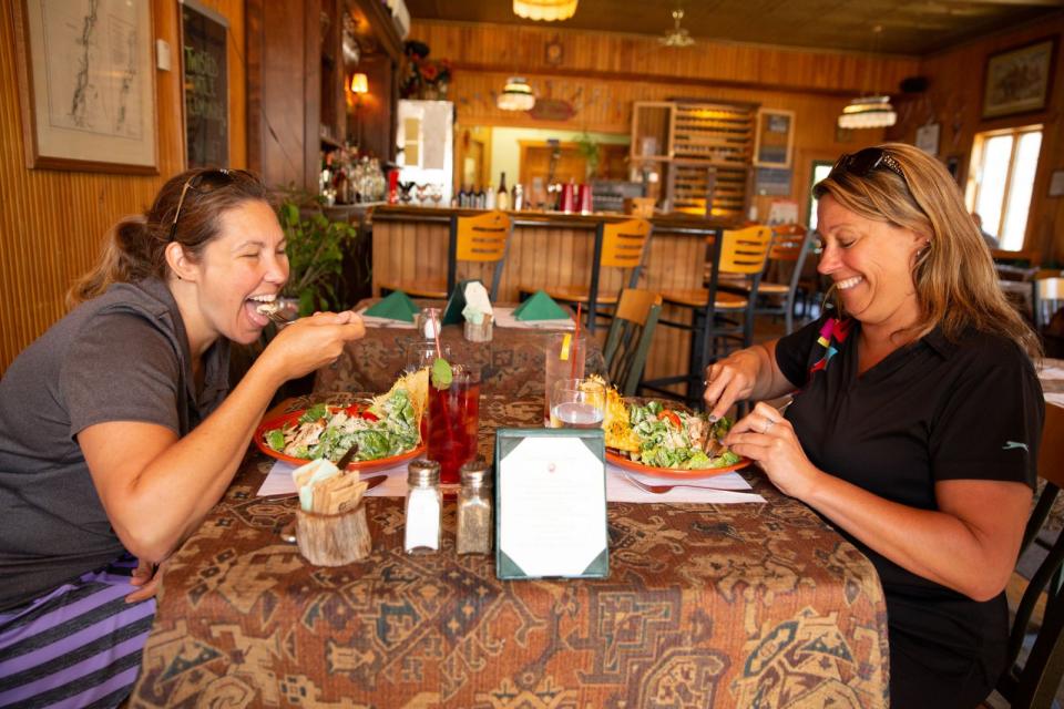 Two women enjoy a meal inside an Adirondack cafe.