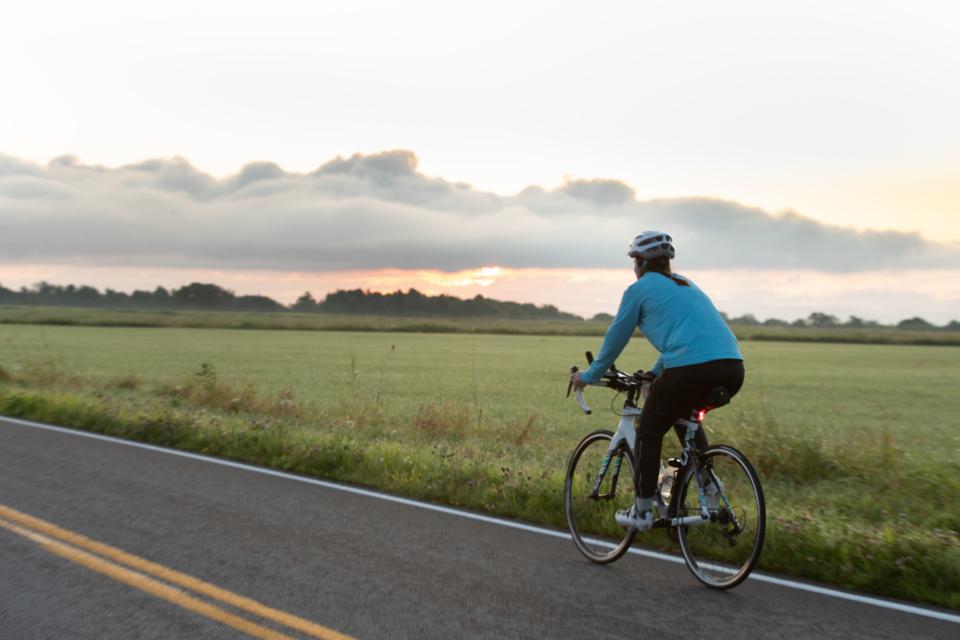 A woman rides a bicycle on a road in the Lake Champlain Region
