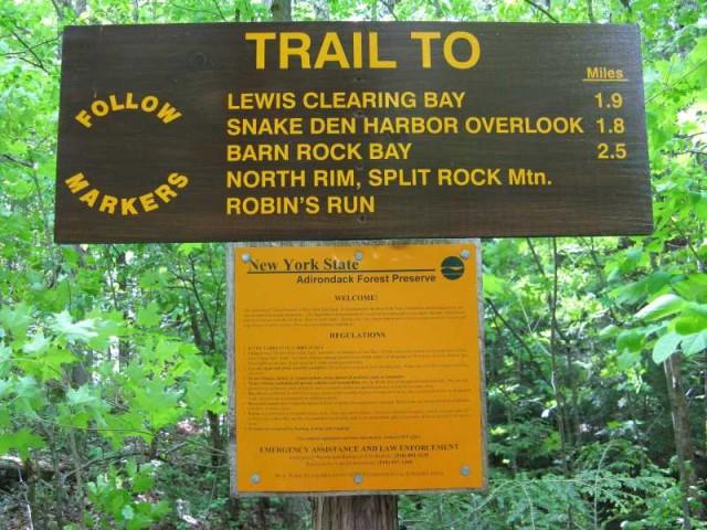 Trail sign to Lewis Clearing Bay and other hikes in a forest preserve.