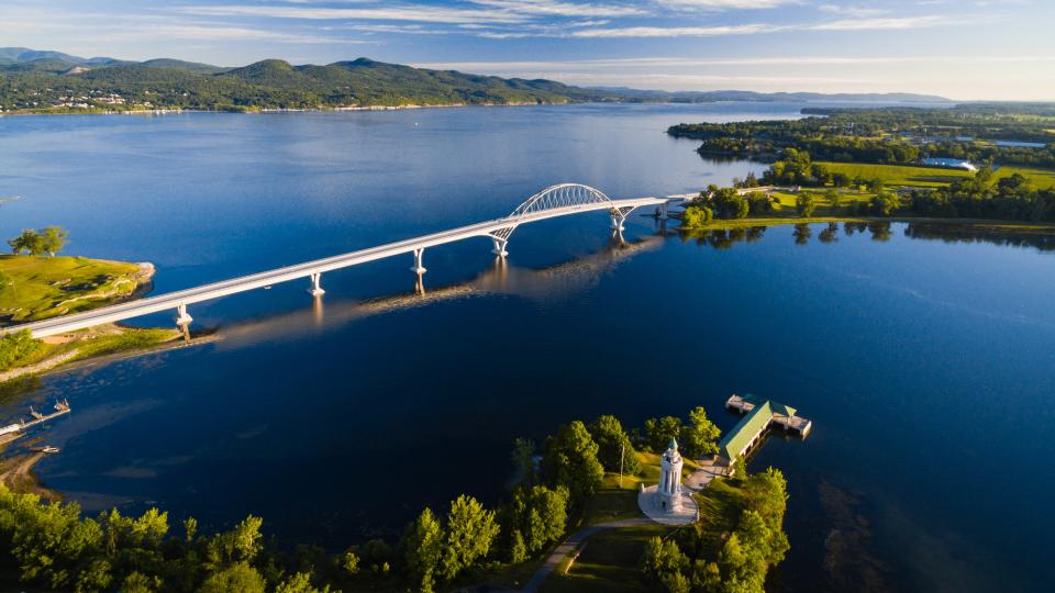 An aerial shot of the Crown Point Bridge shows the vibrant blue of Lake Champlain