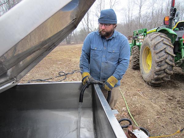 Ken Sayre pumps fresh sap into a holding tank outdoors.
