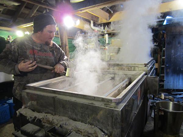 Steam rises over the pans of sap with producer Kevin looking on.
