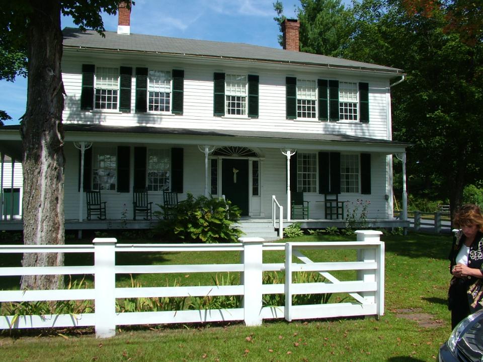 A trim white 19th century home stands on a green lawn.