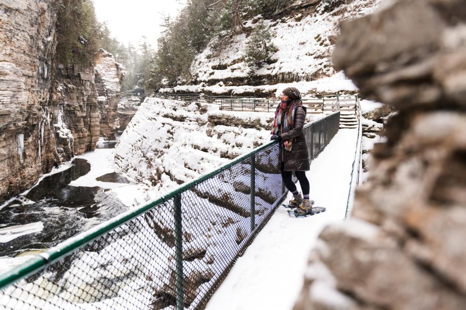 A woman looks out over an icy chasm in the winter