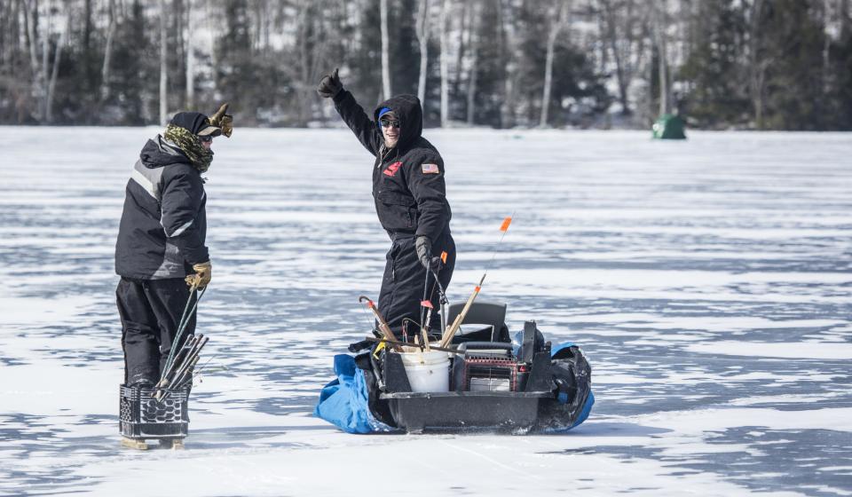 Two men give ice fishing a big, happy thumbs up on the ice.