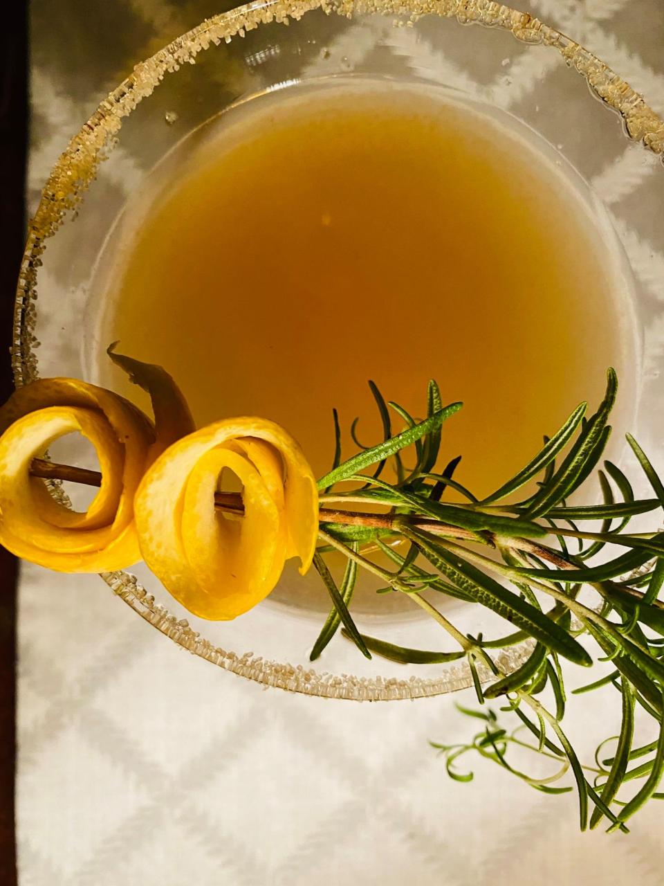 Extreme close-up of a cocktail garnished with thyme and lemon.