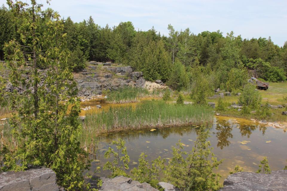 A view down into a quarry with a pool of water at the bottom.