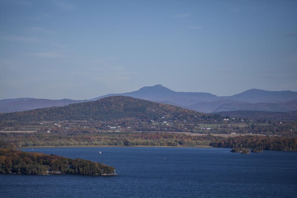 An aerial view of Lake Champlain's blue waters, with Adirondack Mountains and shoreline in the background.