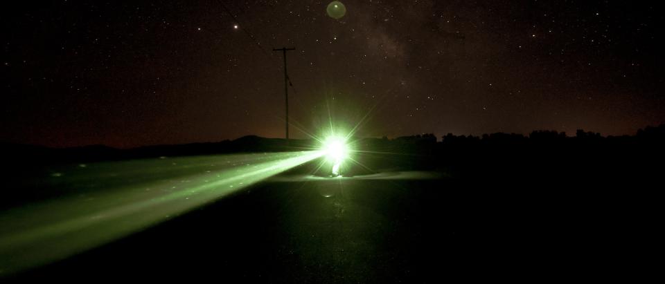 A glowing green light under a starry sky.