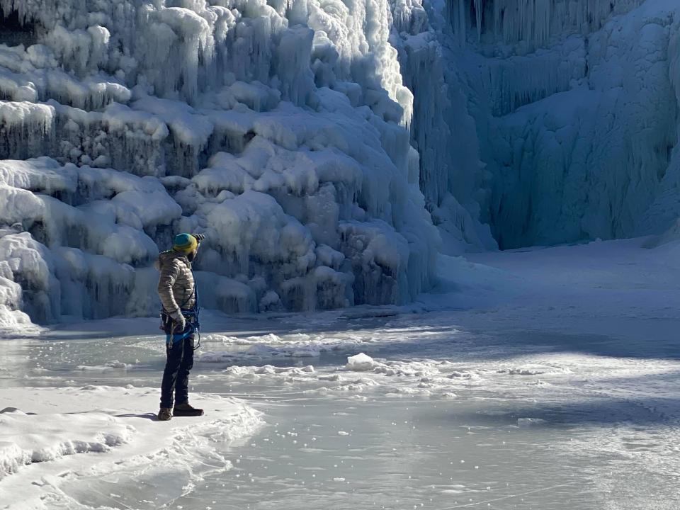 Man looks out at large frozen waterfalls