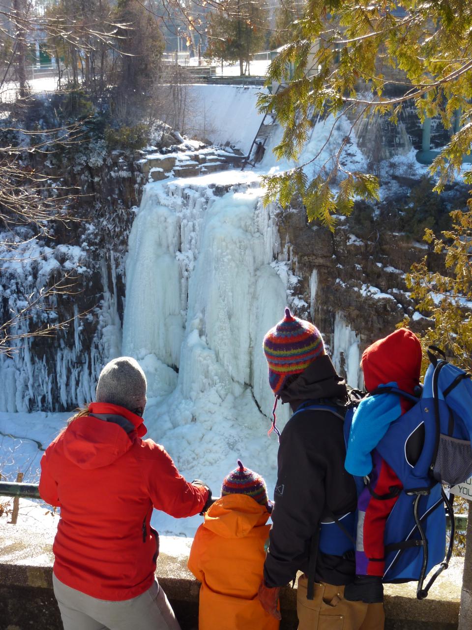 Family looks across river at a large ice formation