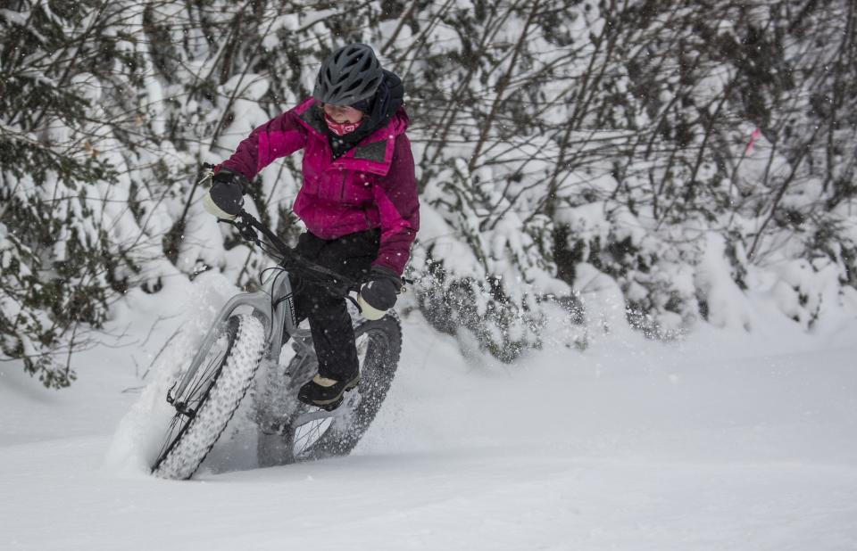 Women slides in the snow on a fat tire bike, nearly tipping over.