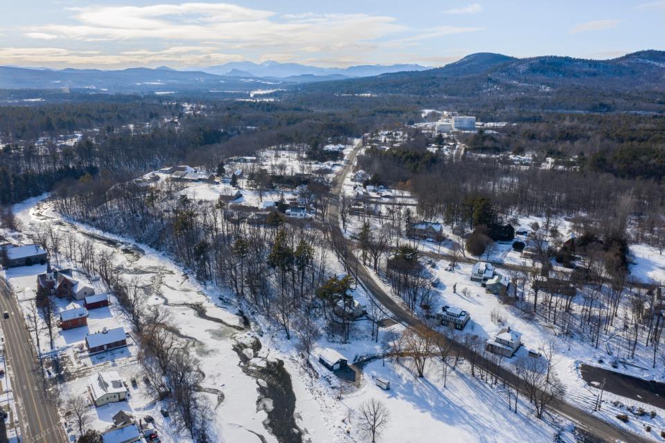 An aerial image of a snow covered town with mountains in the background.