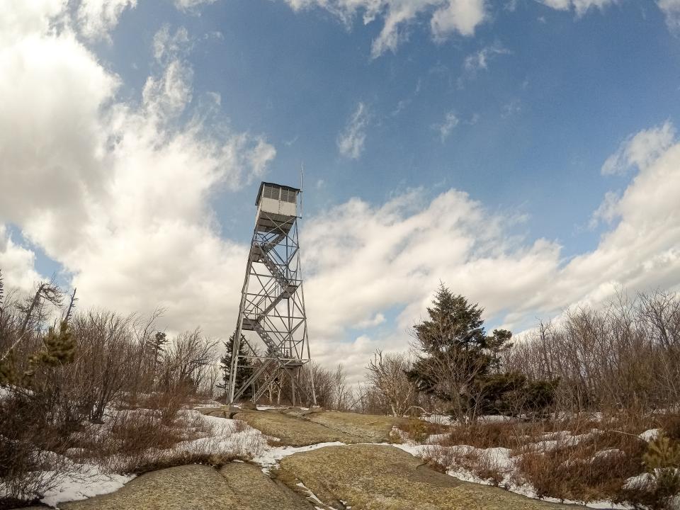 Looking up at a summit fire tower with bare trees all around.