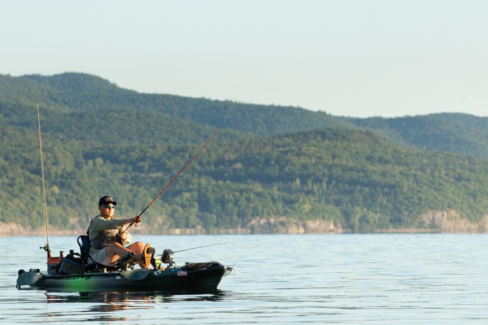 A fisherman casting from a fishing kayak.