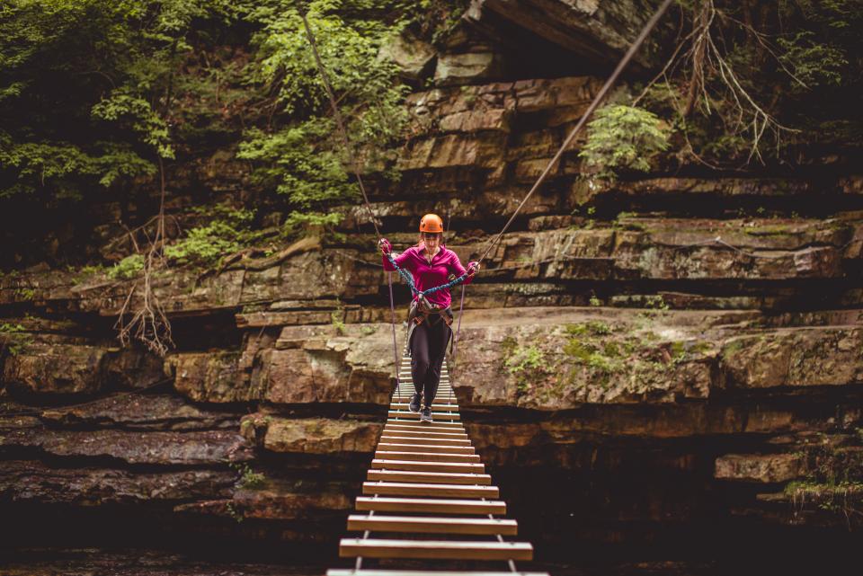 A woman making her way across one of the bridges in Ausable Chasm