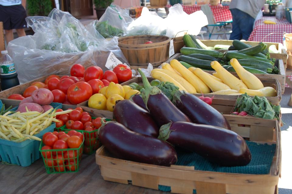 A colorful display of fresh vegetables and fruit at an outdoor farmers market.