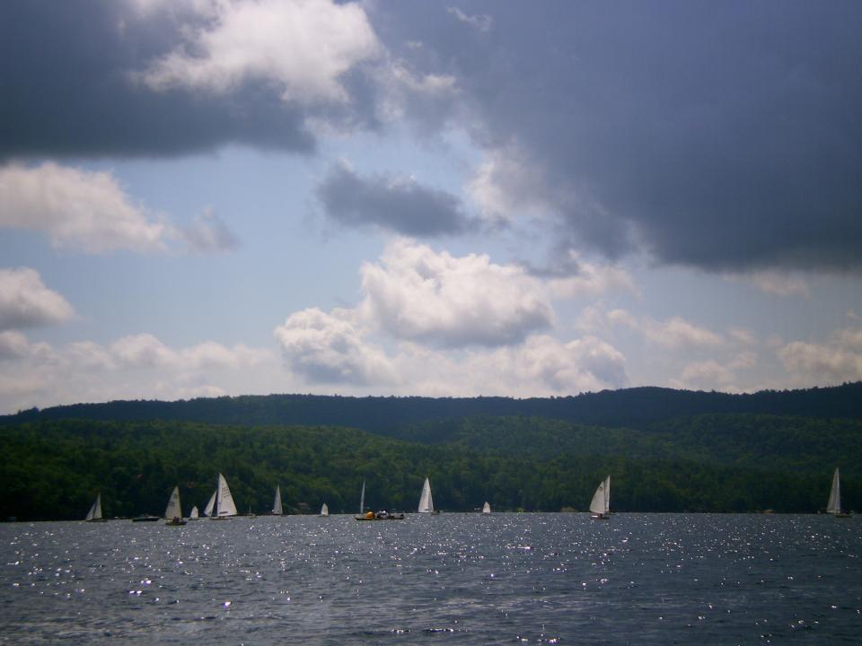 Sailboats on a sparkling lake with a low mountain ridge in the background.
