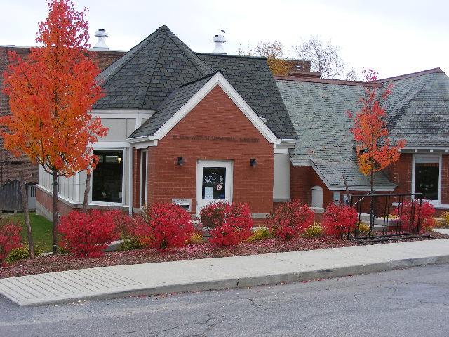 A charming brick library with fall foliage outside.