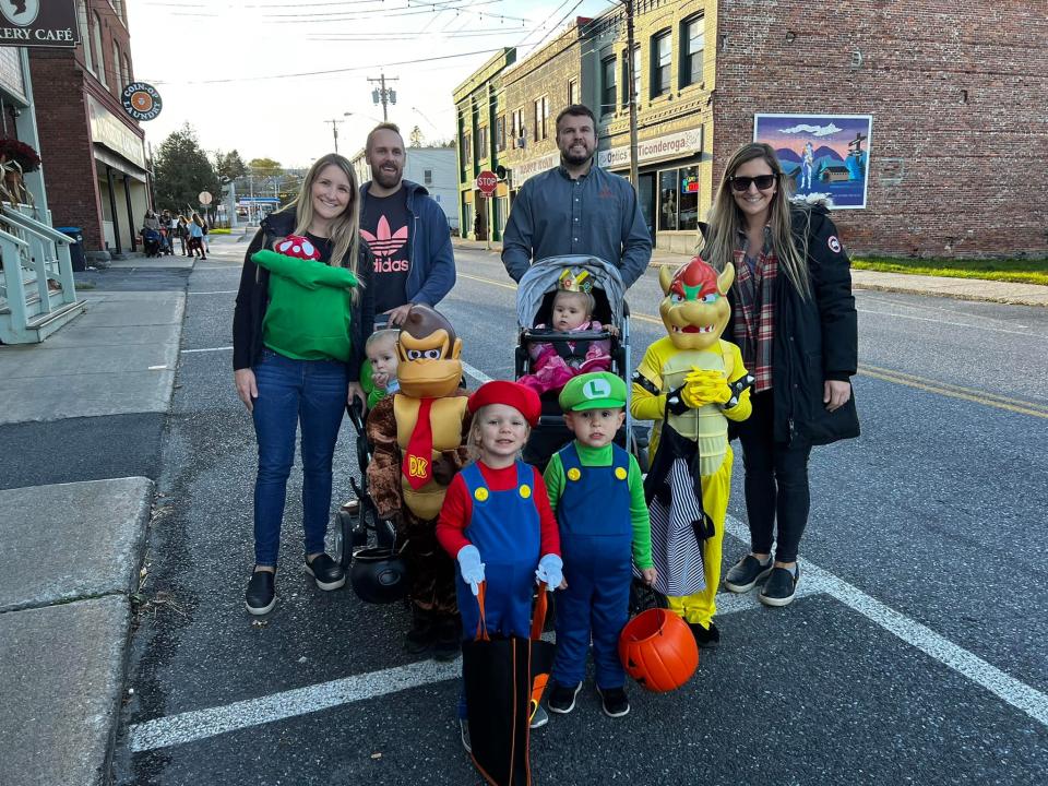 Children in Halloween costumes pose with adults in a quaint downtown.