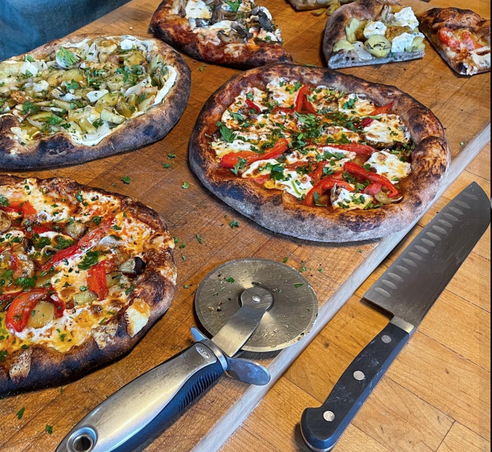 Wood-fired pizzas and kitchen tools displayed for a party