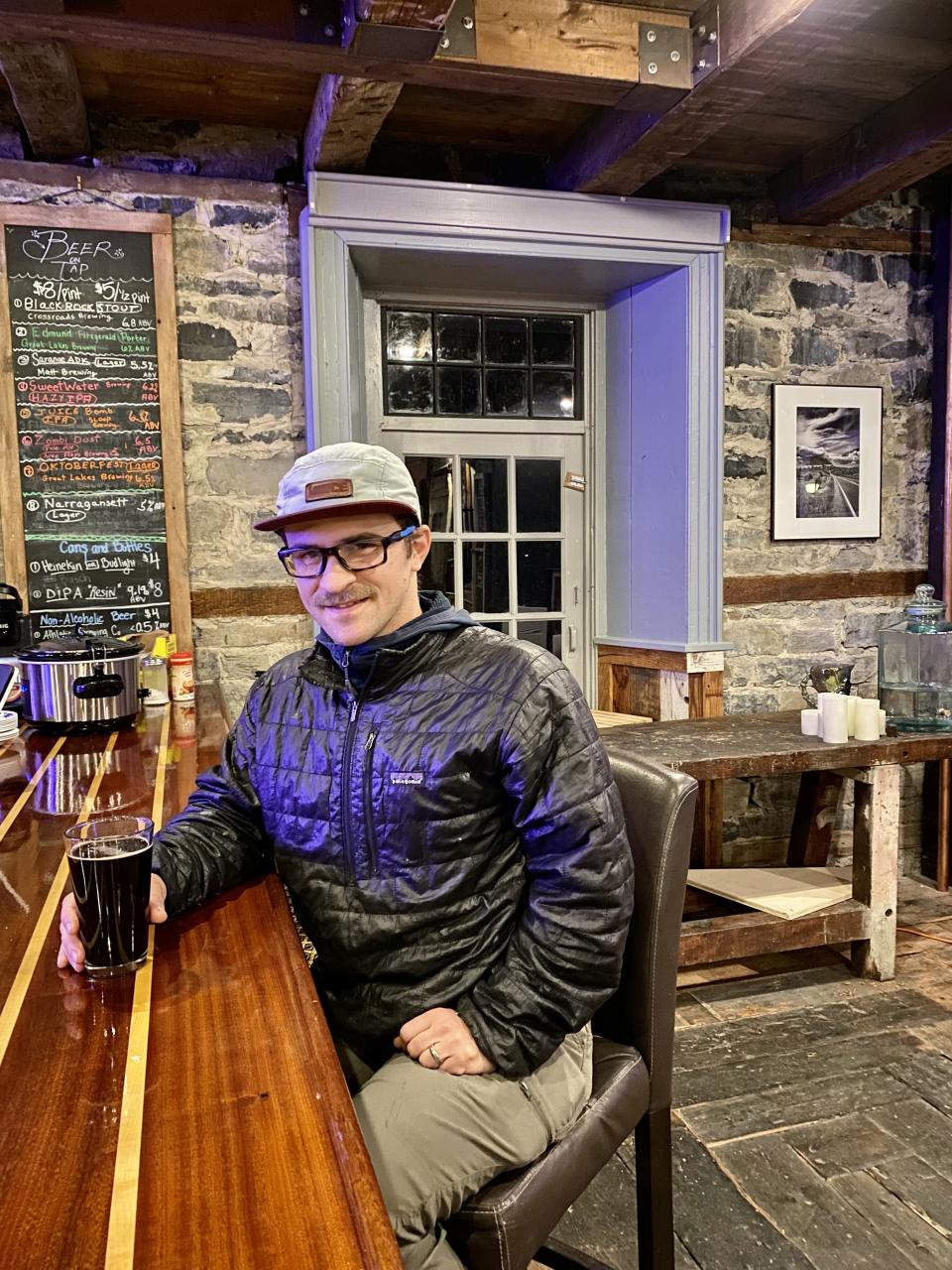 Man enjoying a beer at a bar in a rustic stone building.