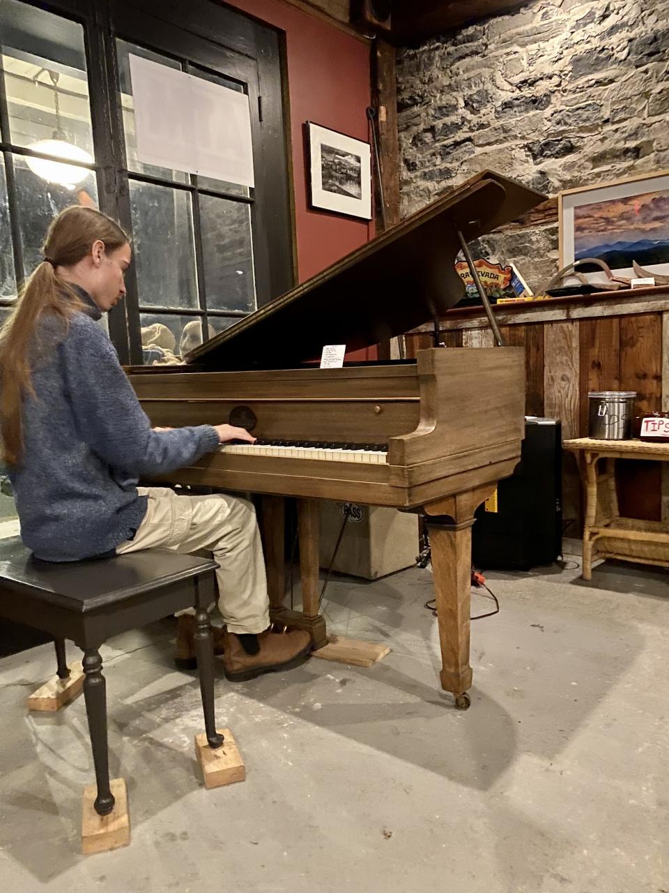 Young man playing piano in a rustic bar.
