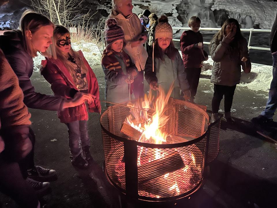 People gathered around a fire roasting marshmallows