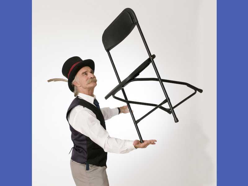 A man balances a metal chair on his hand