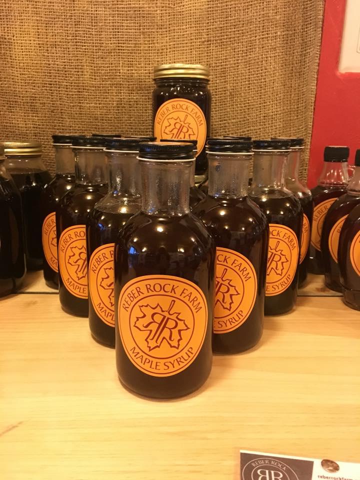A table display of glass bottles full of maple syrup from Reber Rock Farm