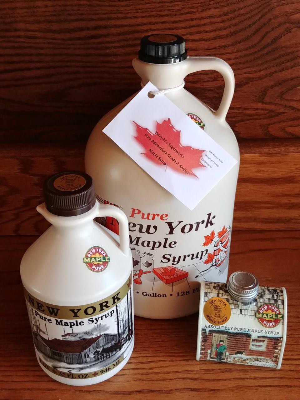 Maple syrup in different sized containers sit on a table in a display