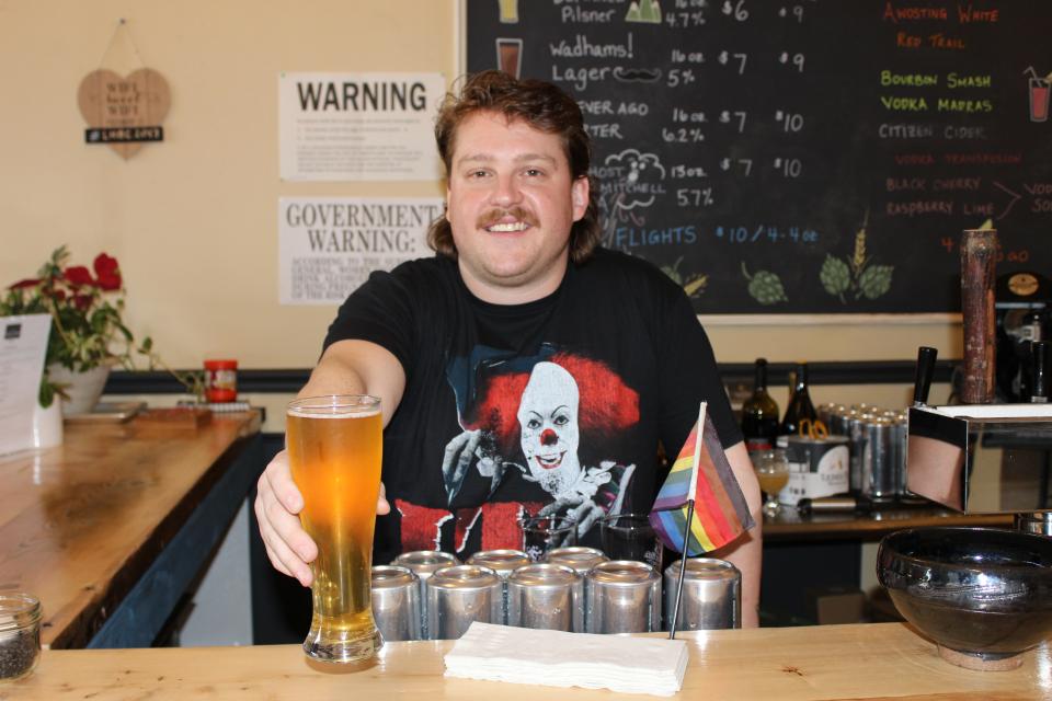 A bartender serves a tall glass of beer