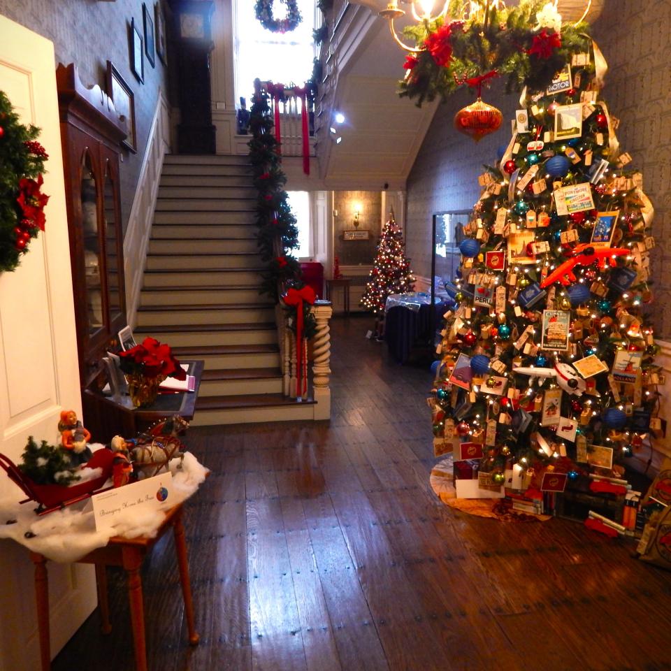A cheerful display of decorated Christmas trees, wreaths, and garlands in a historic home.