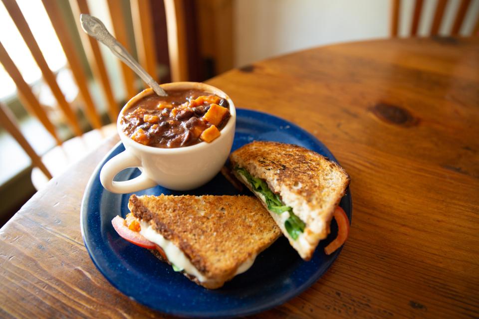 A plate with a grilled sandwich and a side of soup.