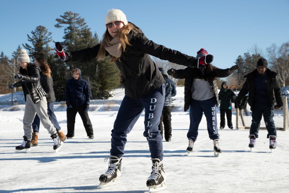 A woman and other ice skaters struggling to keep upright on the ice.