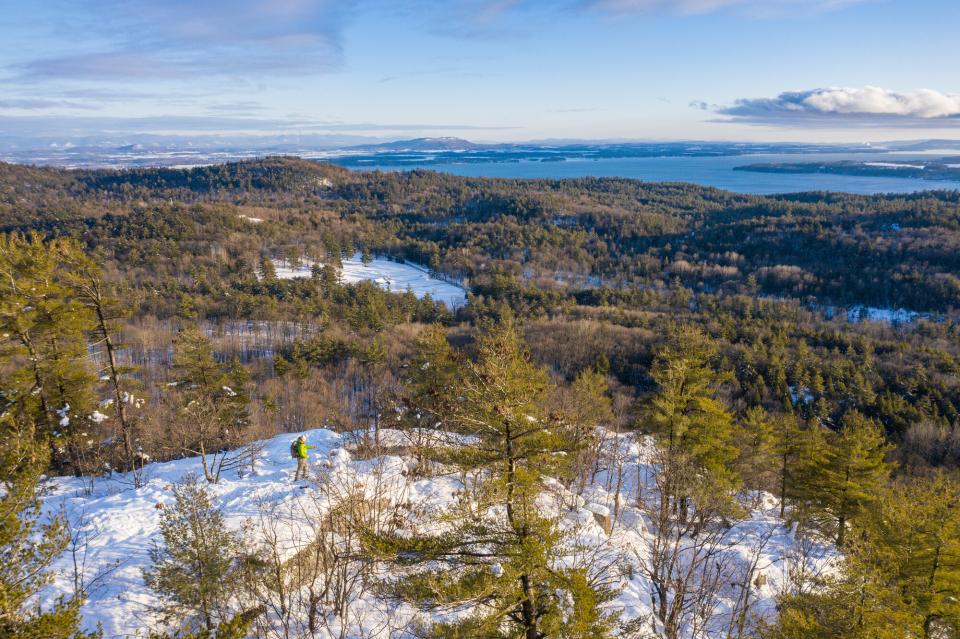 A view from Poke-O-Moonshine mountain, with a sea of snowy mountains and Lake Champlain in the distance